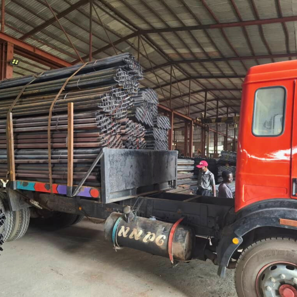 Workers unloading steel rods from truck.