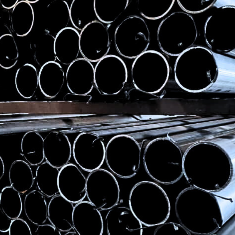 Stacked black metal round pipes in warehouse